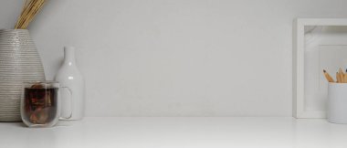 Kopya alanı, kahve fincanı, kalemler ve beyaz masadaki dekorasyonlarla en küçük çalışma alanı görünümünü kapat