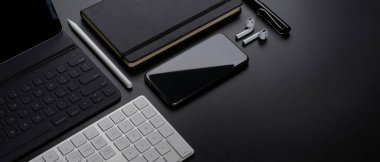 Akıllı telefon, tablet, klavye, kırtasiye, aksesuar ve karanlık masa üzerine kopyalama alanı olan dijital cihazların kırpılmış görüntüsü