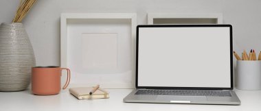 Ev ofis masasının beyaz masadaki dizüstü bilgisayarı, kırtasiyesi ve dekorasyonunu kapat..