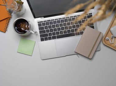 Çalışma alanının en üst görüntüsü laptop, malzeme, kırtasiye malzemesi, aksesuarlar ve beyaz masa üzerindeki dekorasyonlar