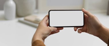 Çalışma alanında kırpma yolu olan yatay akıllı telefonu tutan ellerin görüntüsünü kapat 