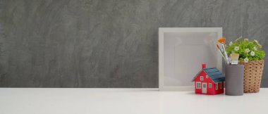 Çalışma alanını boya fırçaları, dekorasyonlar ve tavan arası duvarı olan beyaz masadaki alanı kapat