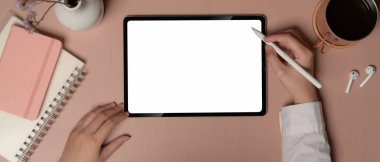 Pembe ofis masasında dijital tabletle çalışan bir kadının, not defterleri ve aksesuarlarla, kırpma yollarıyla....