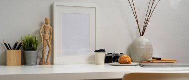 Kırtasiye malzemesi, kamera, dekorasyon, hamur işi ve içecekle beyaz masa üzerinde çalışabilir. 