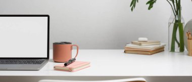 Çalışma alanı görünümünü laptop, kırtasiye, kupa, kitaplar, dekorasyon ve kopyalama alanı ile beyaz masa, kırpma yolu ile kapat.