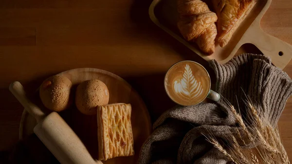 早餐桌上有新鲜烤好的美味面包 拿铁咖啡和木制桌子上的装饰品 俯瞰全景 — 图库照片