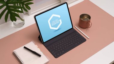 Dijital tablet, aksesuarlar, kırtasiye malzemesi ve dekorasyonla ofis masasında kırpılmış çalışma alanı görüntüsü 