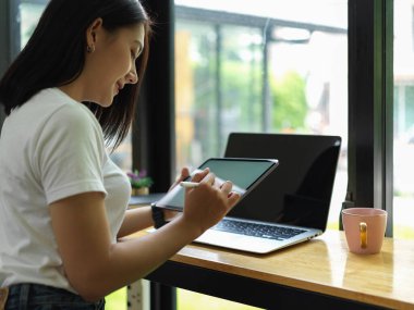 Kafedeki barda tablet ve dizüstü bilgisayarla çalışan serbest çalışan kadın.