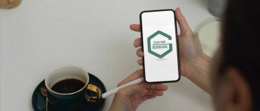 Sıcak kahveyle rahatlarken akıllı telefonları kullanarak kadın ellerini kapat.