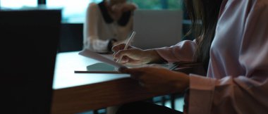 Dijital tabletle çalışan kadın ofis çalışanının yan görünüşü ve toplantı masasında evrak işleri