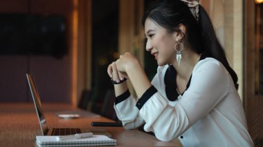 Ortağıyla konferans odasında bilgisayarda konuşurken gülümseyen kadın girişimcinin yan görüntüsü 