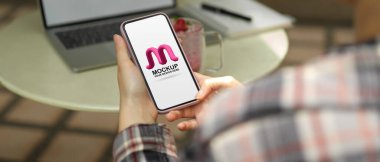 Kadın serbest çalışanın arka bahçede çalışırken akıllı telefonuyla rahatlarken görüntüsü kesilmiş.