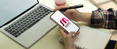 Arka bahçede dizüstü bilgisayarı ve not defteri olan akıllı telefon kullanan kadınların yan görüntüsü.