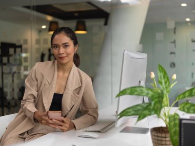 Bilgisayardaki bilgilere bakarken belge dosyasıyla işine odaklanan kadın ofis çalışanının yan görünümü 