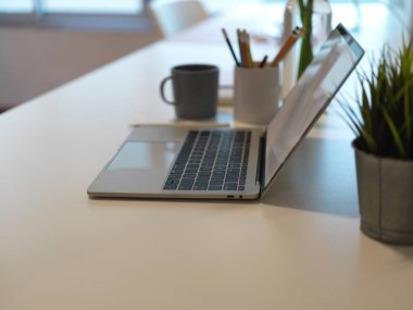 Çalışma odasındaki dizüstü bilgisayar, kırtasiye, dekorasyon ve kopyalama alanının yan görünümü 