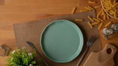 Sahte tabakla yemek masasının üst görüntüsü, servis altlığında gümüş eşyalar ve ahşap masa süslemeleri.  