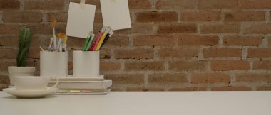 Çalışma alanını kırtasiye malzemeleri, boya araçları, kahve fincanı, dekorasyon ve beyaz masadaki kopyalama alanı ile kapat 