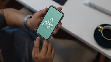 Ofis odasında rahat bir şekilde otururken akıllı telefon ekranı kullanarak erkek ofis çalışanının kırpılmış görüntüsü. 
