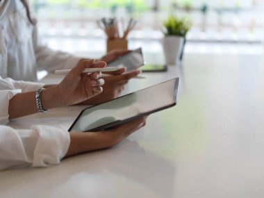 Kütüphanede yan yana otururken dijital tablet kullanan kadınların yan görünümü 