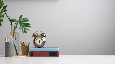 Kitaplar, kırtasiye malzemeleri, boya araçları, saat, bitki vazosu ve ev ofisindeki kopyalama alanı ile çalışabilir görünümü kapat 