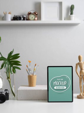 Dijital tablet, kamera, malzeme, dekorasyon ve fotokopi alanı ile modern ev ofisinin kırpılmış görüntüleri.  
