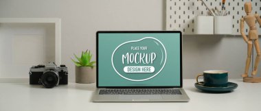 Çalışma odasındaki kamera, kahve fincanı ve dekorasyonlarla birlikte kullanılabilir bir dizüstü bilgisayarın görüntüsünü kapat