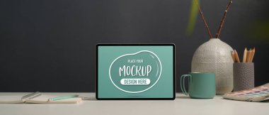 Ofis masasının görüntüsünü kapatıyoruz. Tablet, tasarımcı malzemeleri, vazo ve kahve fincanı ofis odasında.