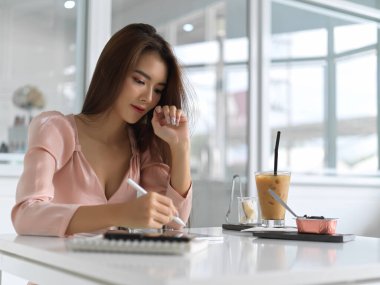 Genç ve güzel bir iş kadını çalışma odasında tablet hazırlıyor. 