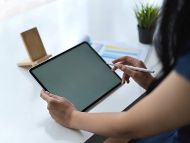 Modern çalışma alanında boş ekran tabletle çalışan genç bayan tasarımcının kırpılmış görüntüsü 