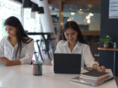 Genç profesyonel iş kadınları modern ofis odasında projeleri üzerinde birlikte çalışıyorlar. 