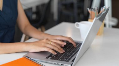 Ofis odasında projesi üzerinde çalışırken dizüstü bilgisayarda yazı yazan genç bir kadının görüntüsü. 