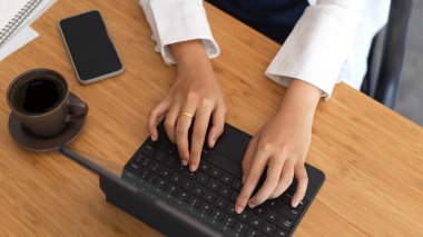 Genç bir iş kadınının tahtadaki tablet klavyeye yazı yazarken görüntüsü. 