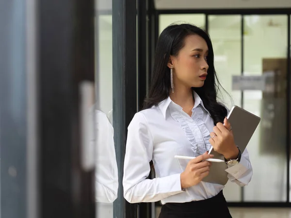 Portrait of female worker holding digital tablet while standing in front of the door to meeting room