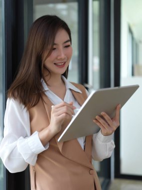 Kütüphanede dururken sunum hazırlamak için dijital tablet kullanan kadın üniversitesinin portresi 