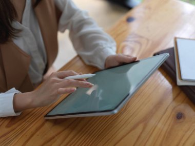 Tahta masadaki dijital tabletle ödev yapan kız öğrencinin kırpılmış fotoğrafı. 