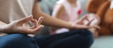 Kanepede uzanmış, elleri kucağında meditasyon yapan, oturma odasında yoga yapan bir kadının yan görüntüsü.