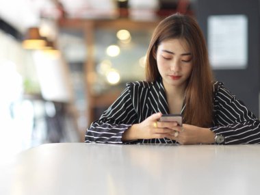 Bayan ofis çalışanının portresi ofis odasındaki masada akıllı telefonuyla mola verir. 