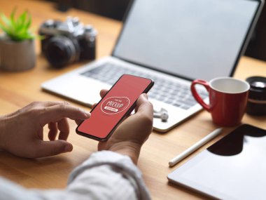 Ofiste dizüstü bilgisayar, kamera ve tabletle çalışırken erkek akıllı telefon kullanıyor. 