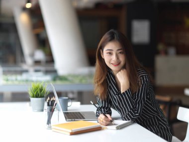 Çalışabilir bilgiler okurken gülümseyen ve kameraya bakan kadın ofis çalışanının portresi 