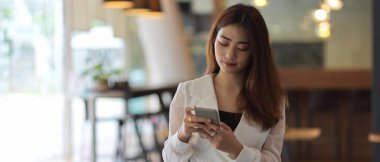 Ofiste dinlenirken akıllı telefon kullanan iş kadınının portresi