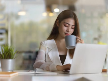 Ofiste dizüstü bilgisayarla çalışırken kadın ofis çalışanının portresi kahve molası verir. 