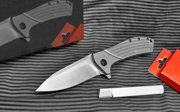 Folding knife stainless steel sharp blade red paper box blue background