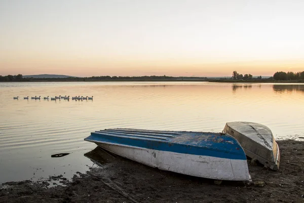 日落时分在湖面上倒置的船 — 图库照片