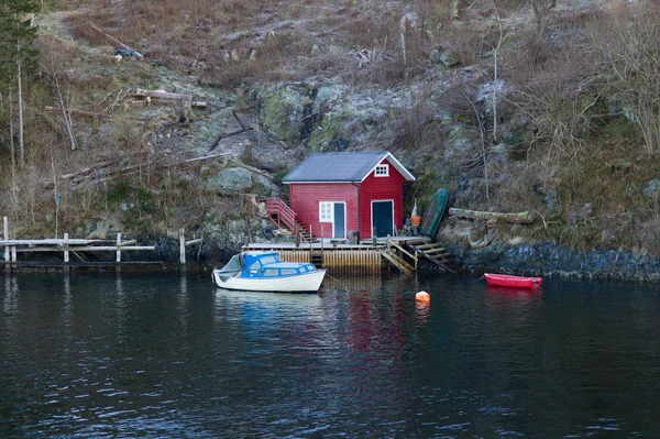 Typical red scandinavian house at fjord in front of snow covered mountains in winter