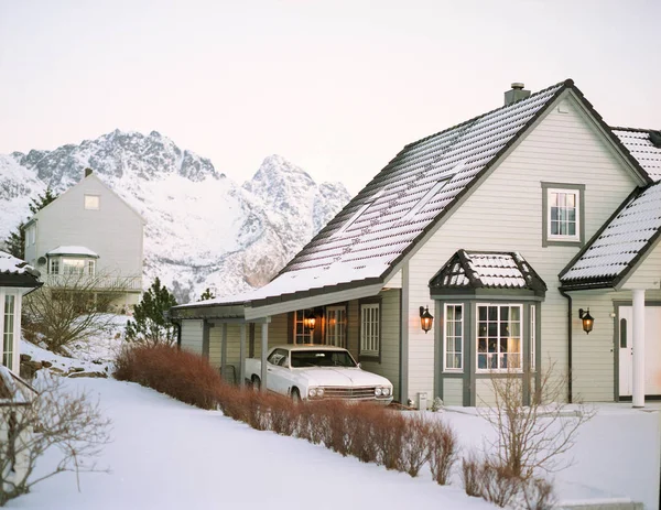 Typical scandinavian house at fjord in front of snow covered mountains in winter