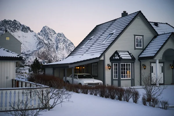 Typical scandinavian house at fjord in front of snow covered mountains in winter