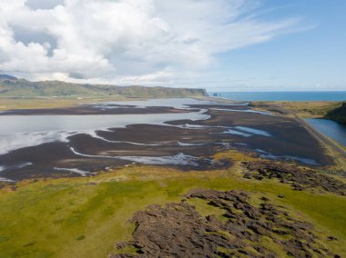 İzlanda'da siyah kum plaj ve yeşil çim eniyip mavi deniz