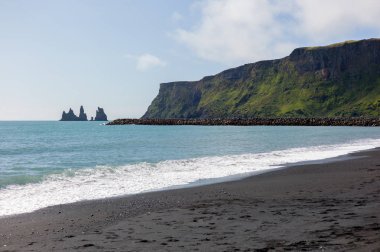 İzlanda'da siyah kum plaj ve yeşil çim eniyip mavi deniz