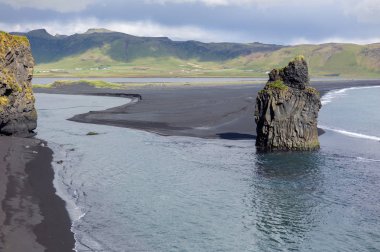 İzlanda'da siyah kum plaj ve yeşil çim eniyip mavi deniz