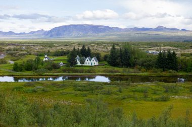 Beyaz İskandinav evlerinin panoramik görünümü, suda yansıması, bulutlu havalarda tepeler 